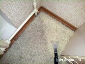 Процесс очистки ковра под диваном